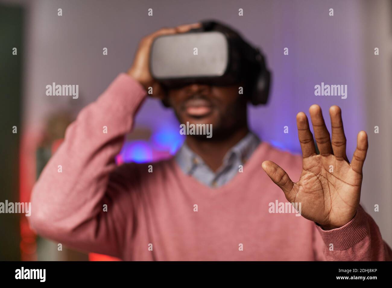 African man in virtual reality glasses gesturing while playing online game Stock Photo
