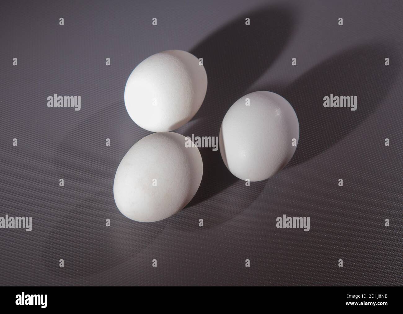 three white chicken eggs on grey background Stock Photo - Alamy