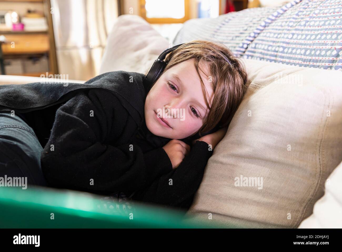 Young boy lying on sofa looking at laptop computer Stock Photo - Alamy