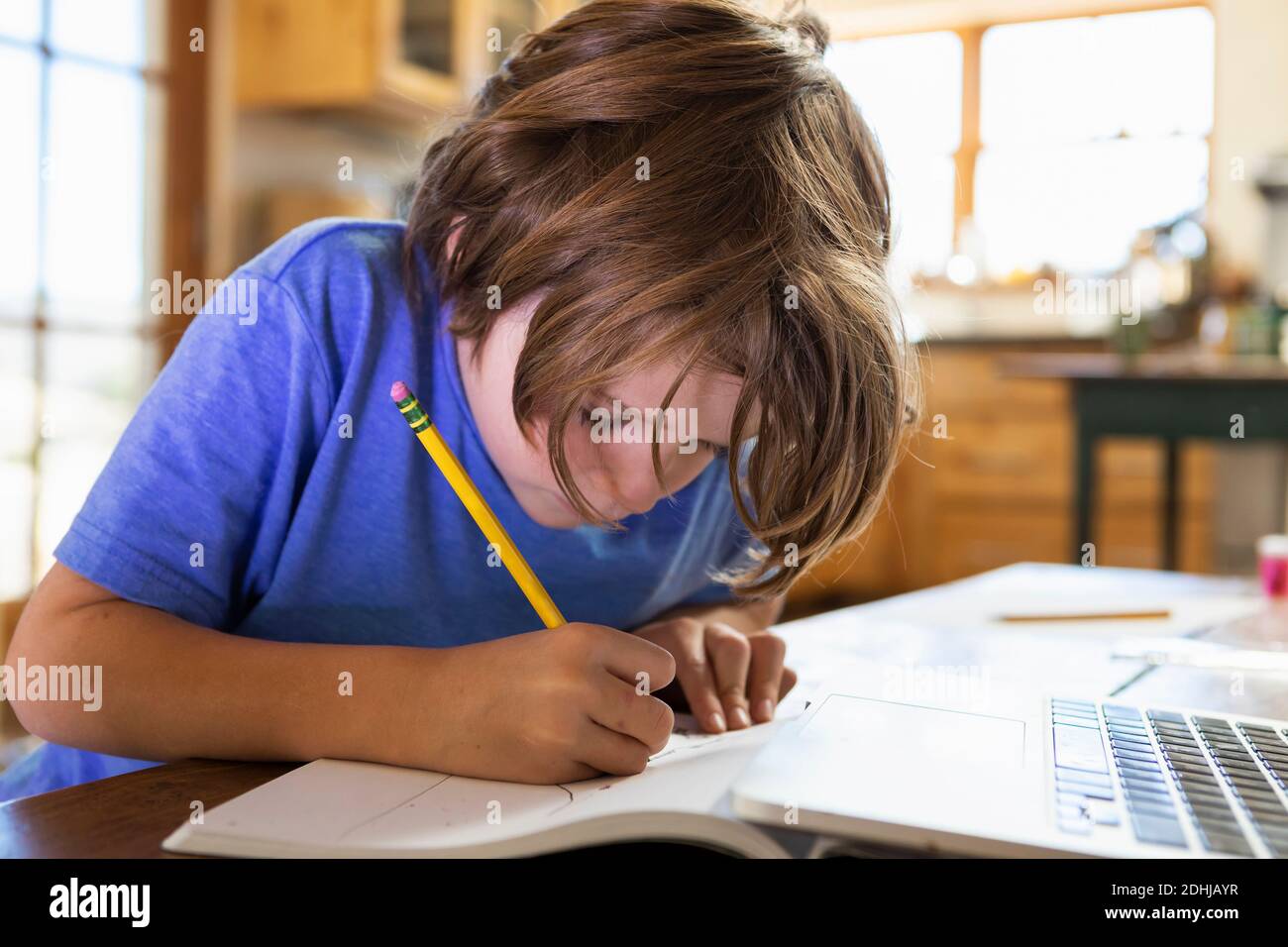 Young boy at home writing and drawing in his drawing pad Stock Photo