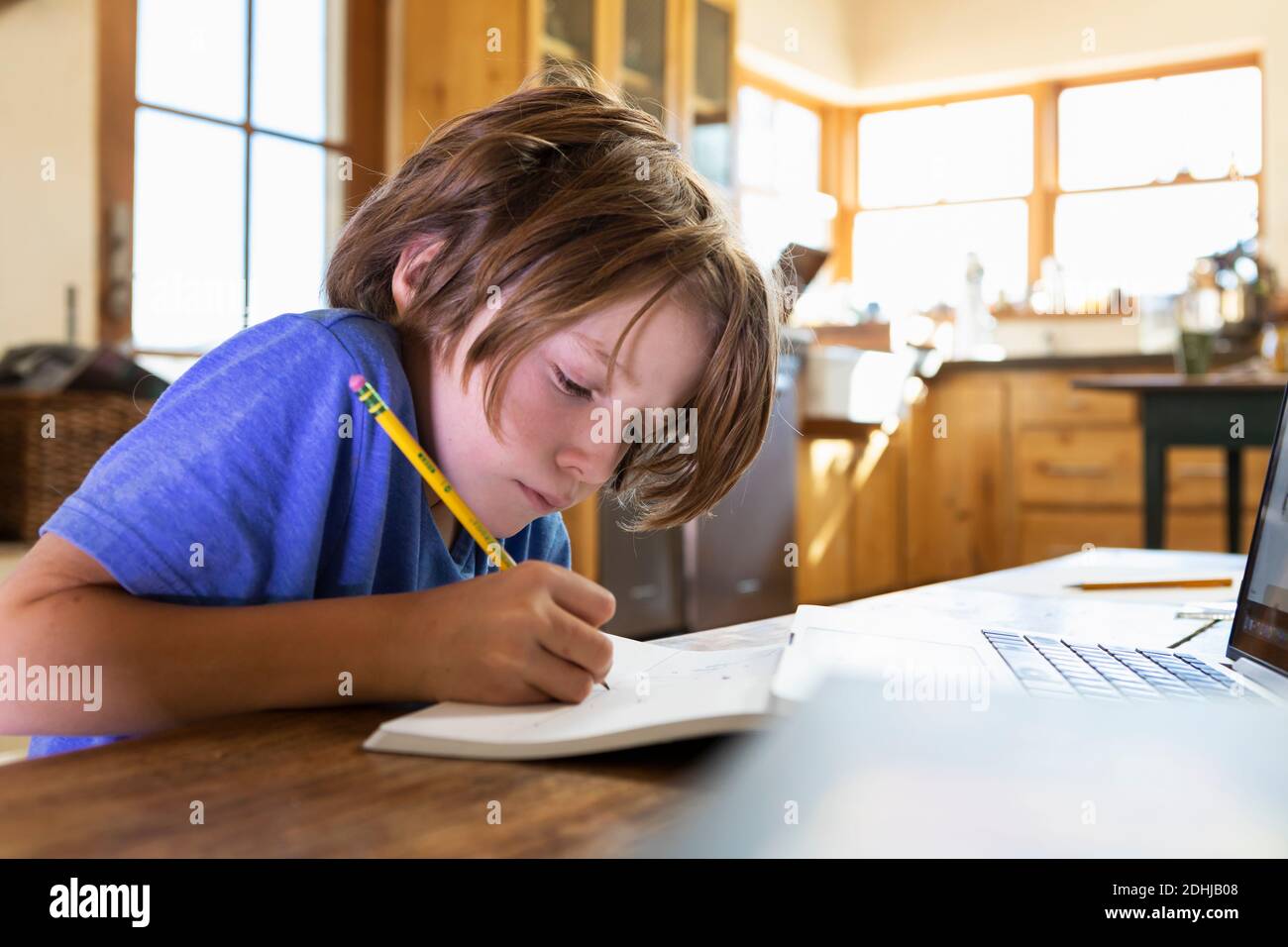 Young boy at home writing and drawing in his drawing pad Stock Photo