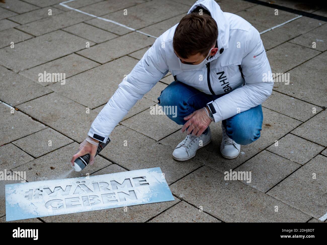 Hamburg, Germany. 11th Dec, 2020. An employee of Hamburger Hochbahn sprays the hashtag 'Wärme Geben' on the sidewalk of Jungfernstieg. The heat bus of the Hochbahn supports the campaign #wärmegeben of Hanseatic Help and collects donations in kind for homeless people. Credit: Axel Heimken/dpa/Alamy Live News Stock Photo