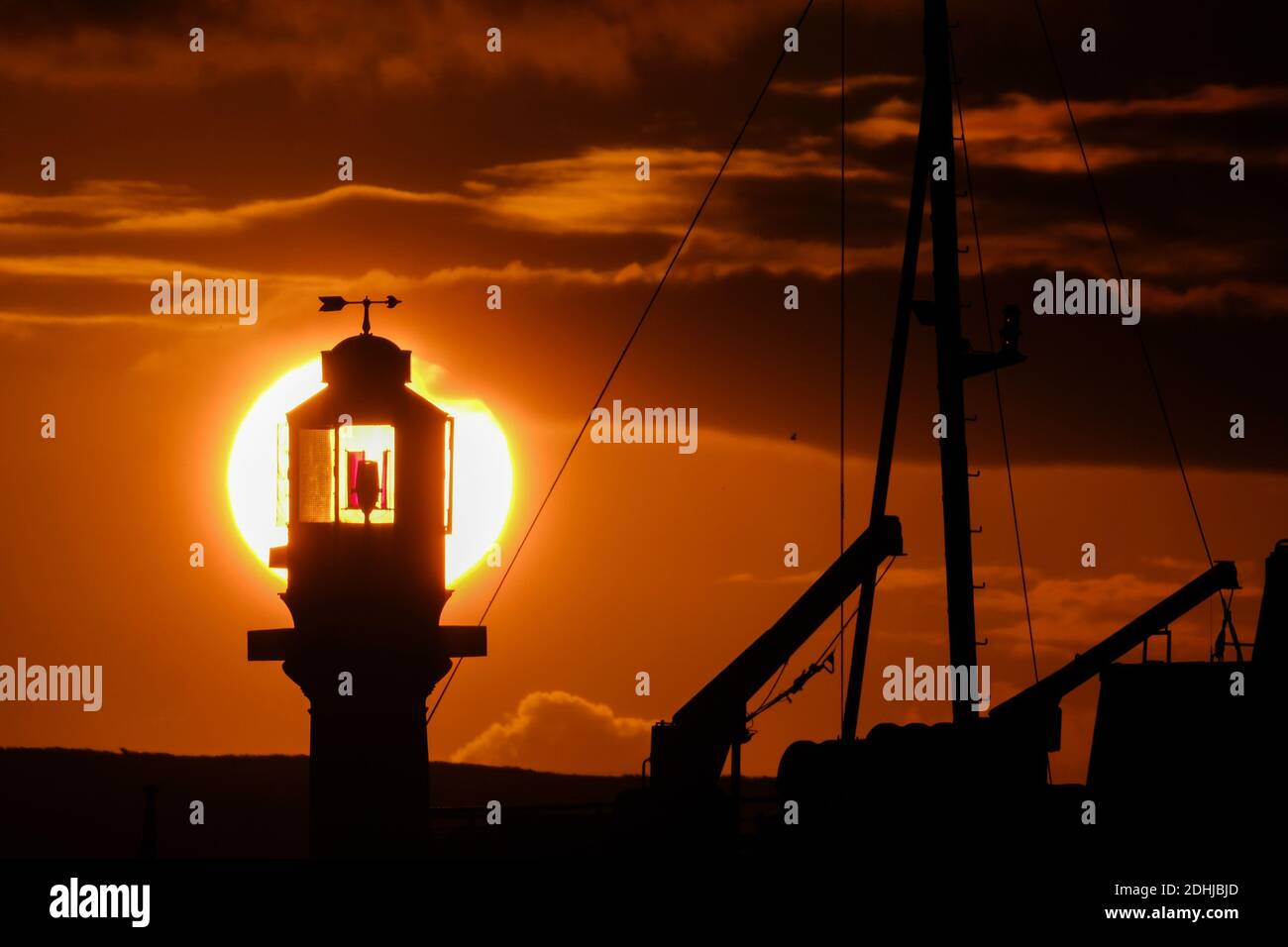 The calm before Storm Alex, as the sun rises behind Penzance harbour lighthouse on the first day of October. Stock Photo