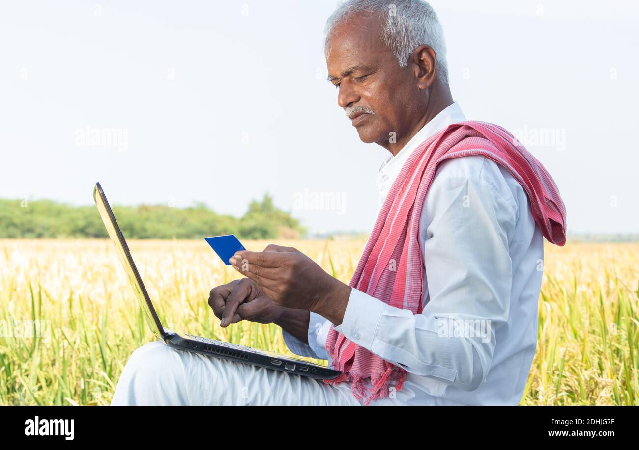 Indian farmer on laptop doing payment by using credit card concept of