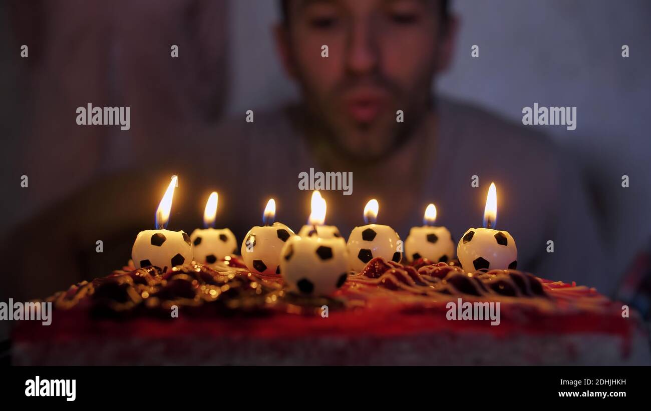 Father football player lights a cake with soccer candles with children