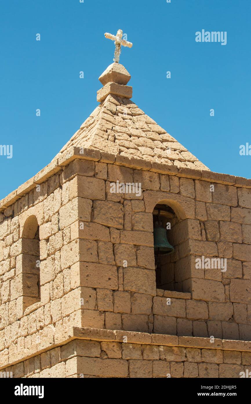 The church tower of San Bartolome, with a crooked cross, at Socaire, the Andes, near San Pedro de Atacama,Chile Stock Photo