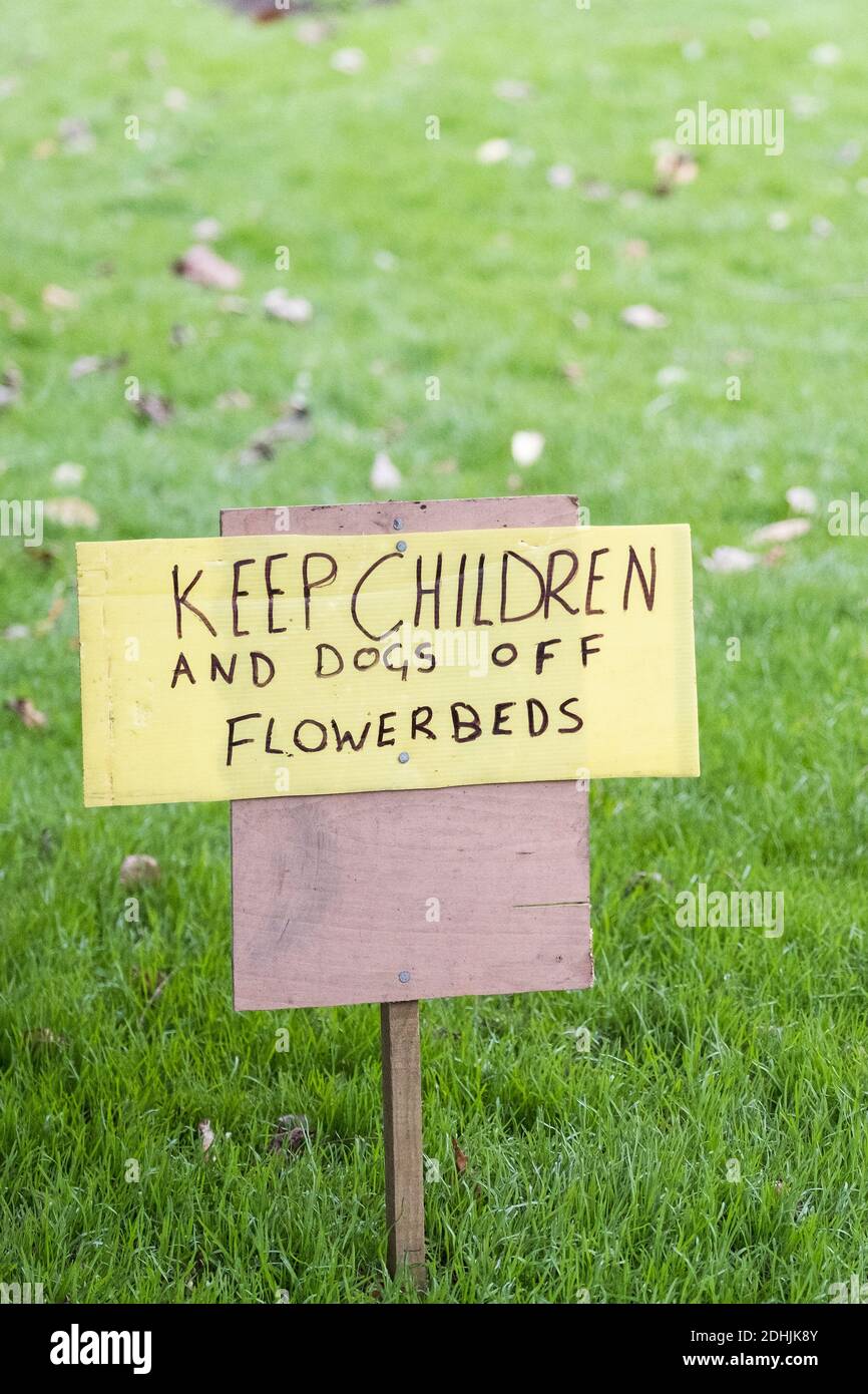 A handwritten sign requesting that children and dogs keep off flowerbeds. Stock Photo