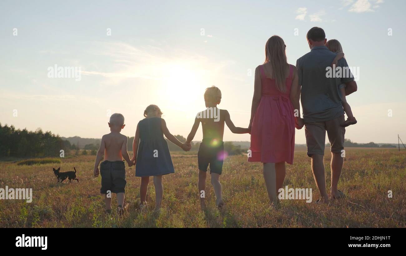 A friendly large family walks across the field at sunset Stock Photo ...