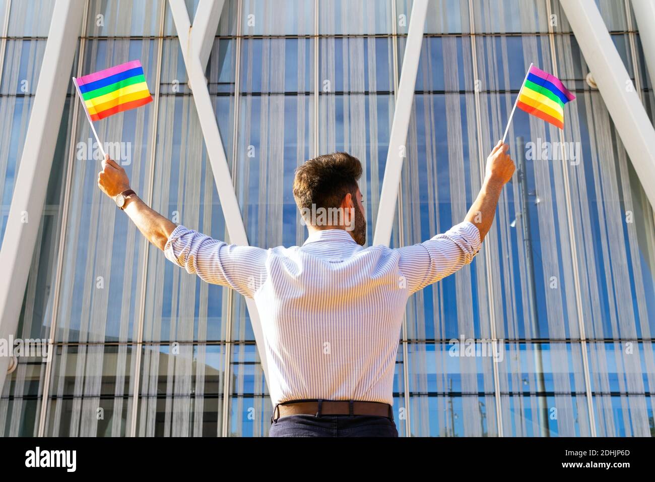 Back view low angle of homosexual male standing on street with paper ...