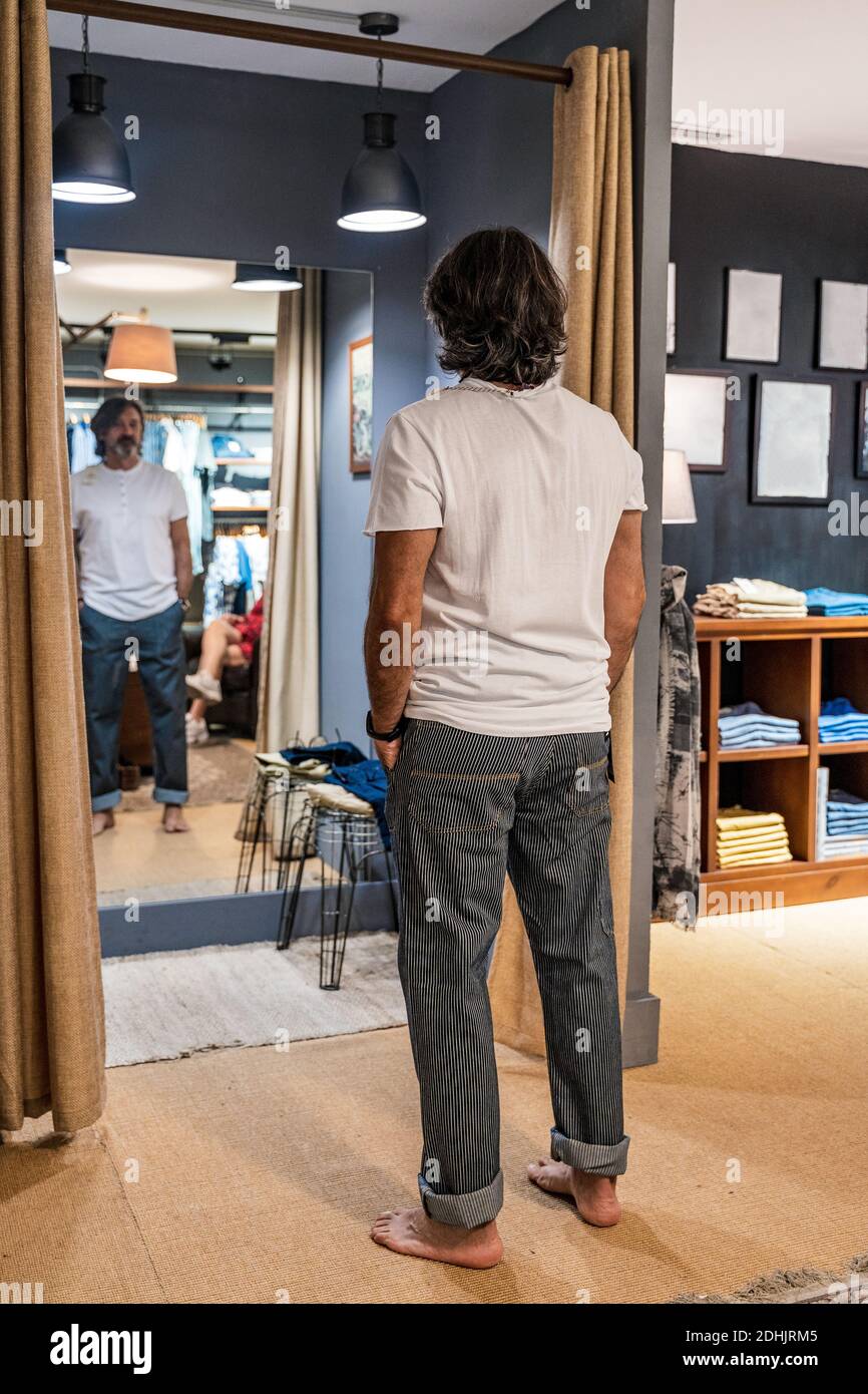 Back view of satisfied man looking at himself in the mirror of a