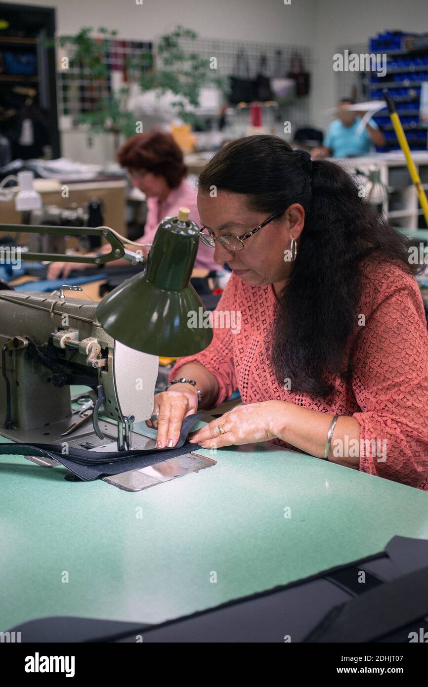 Female worker in at luggage maker Samsonite is sewing with sewing machine, Mansfield,Massachusetts ,United States. Stock Photo
