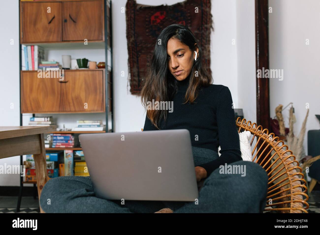 Low angle of serious Indian female sitting with laptop and reading news online Stock Photo