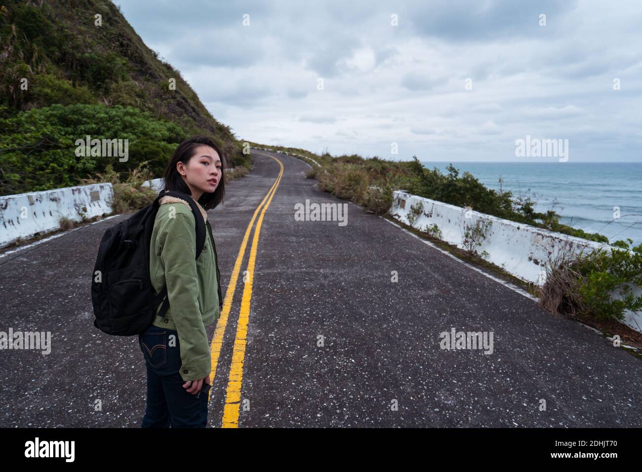 Side view of active female hiker with backpack walking on asphalt road ...
