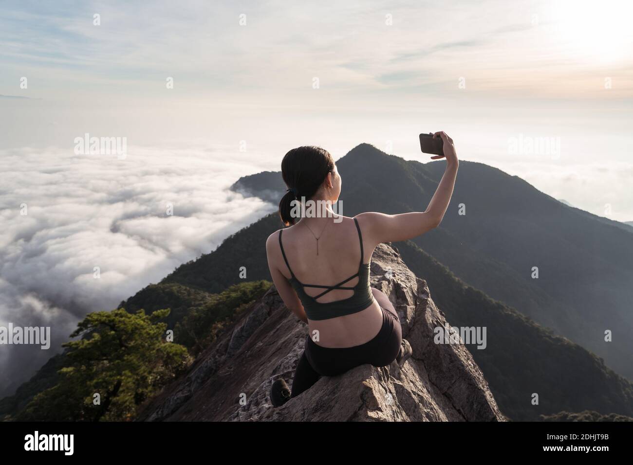 Back view of female ethnic hiker sitting on top of Yuanzui Mountain and ...