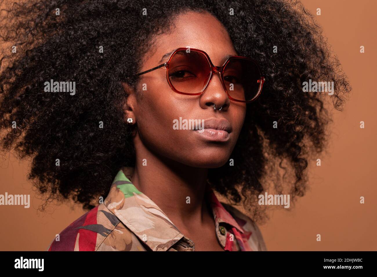 Confident Cuban Woman with Afro hairstyle wearing sunglasses with floral shirt looking at camera Stock Photo