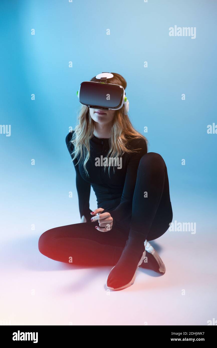 Young unrecognizable blonde Woman sitting wearing virtual reality ...