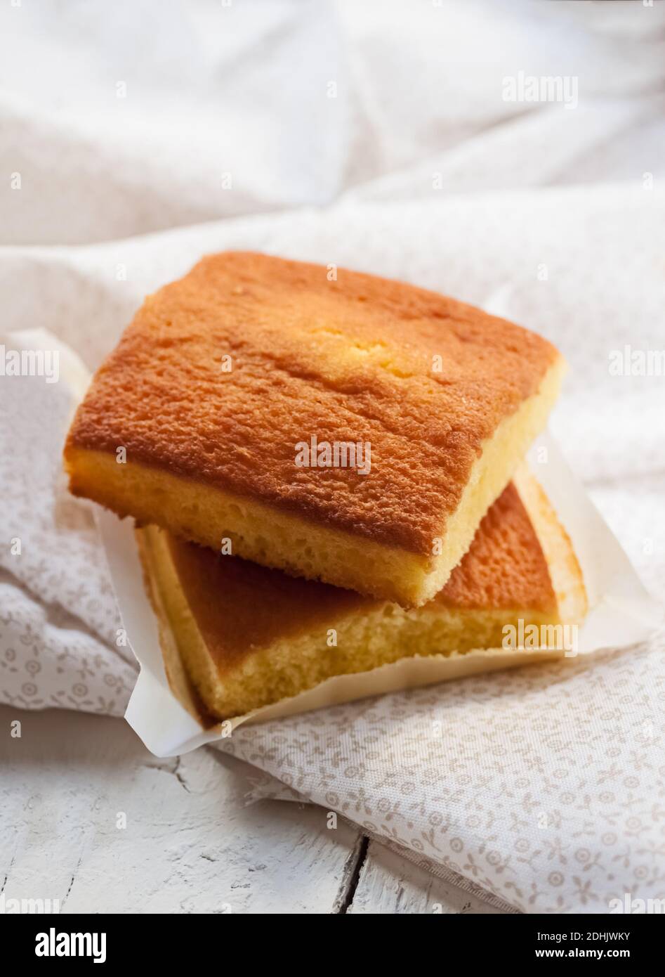 Yummy sweet baked Spanish sobao pasiego cakes served on white wooden table with napkin Stock Photo