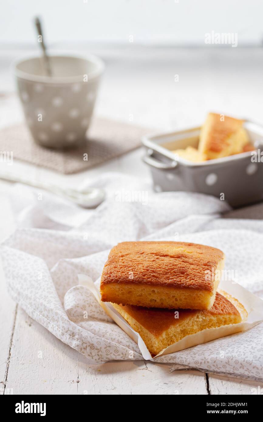 Typical Spanish sobao pasiego cakes served for breakfast with cup of hot drink on wooden table with tablecloth Stock Photo