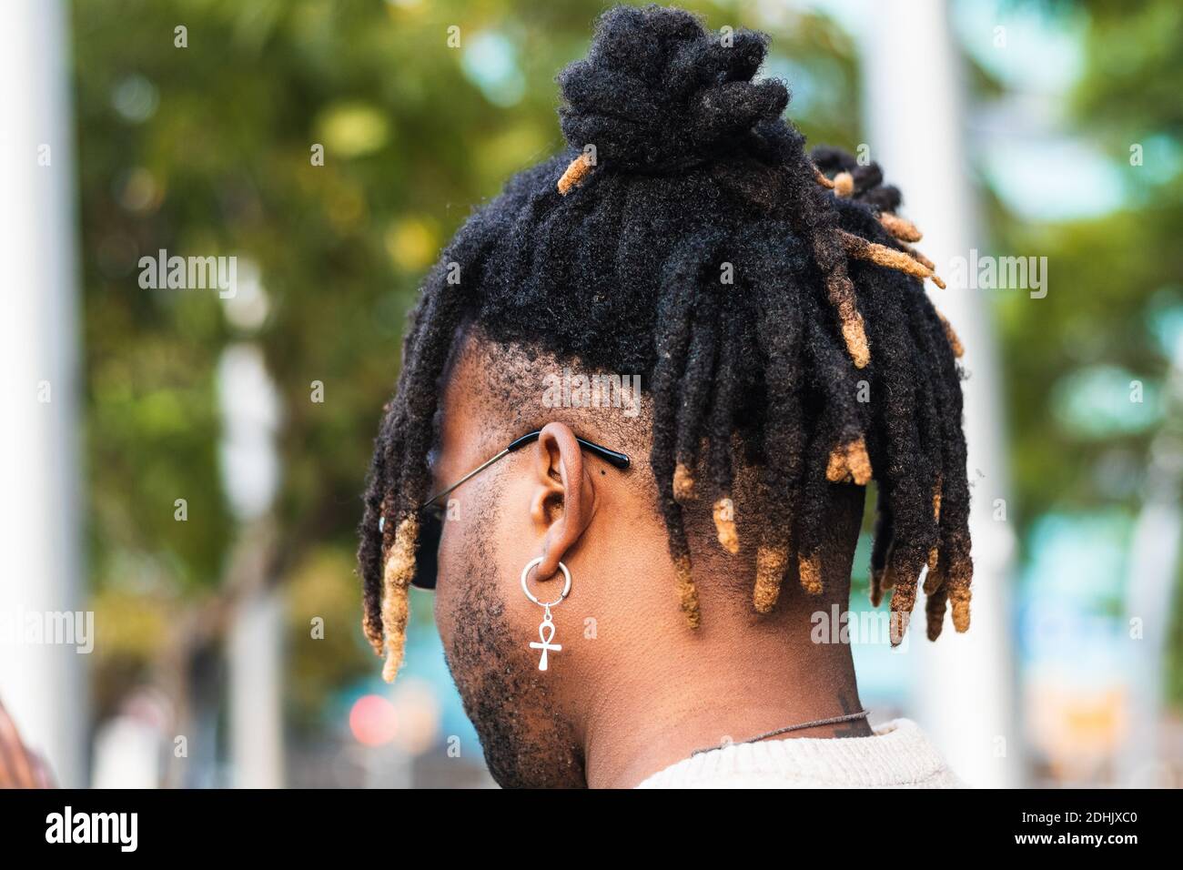 Back View Of African American Man With Dreadlocks In Bun Wearing Ankh Earring With Sunglasses On Blurred Street Background Stock Photo Alamy