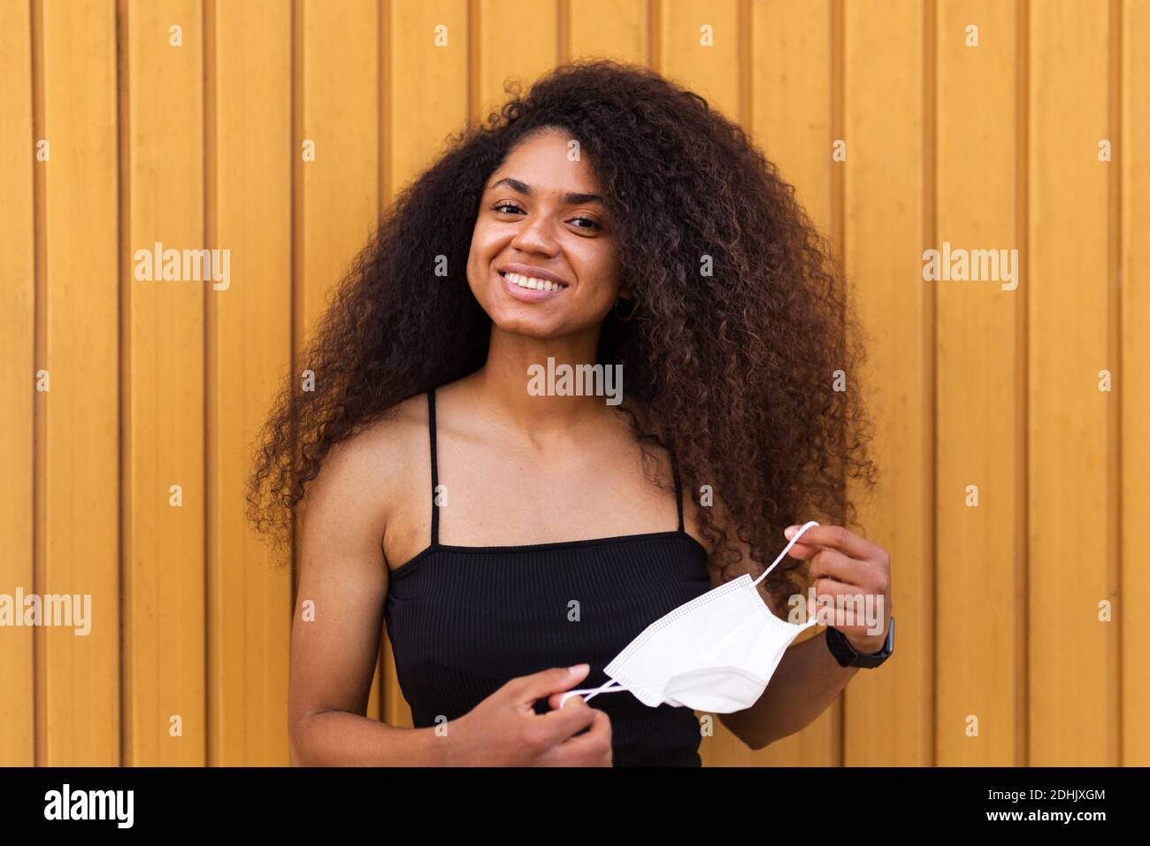 Delighted African American female with Afro hairstyle looking at camera on red background in studio Stock Photo