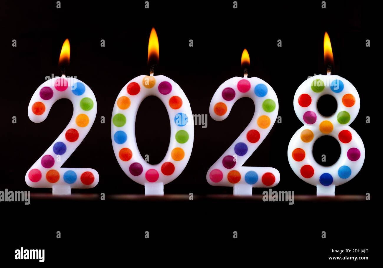 Four colored candles write numbers flame happy new year 2028 black background Stock Photo