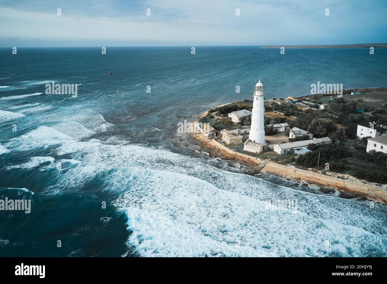 From above drone view of white lighthouse tower and small settlement ...