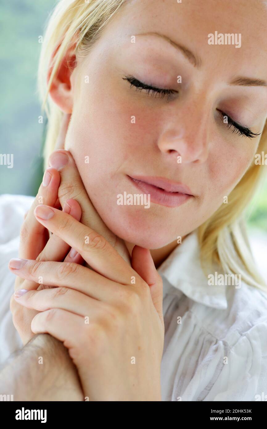 woman with her partners hands touching her face Stock Photo