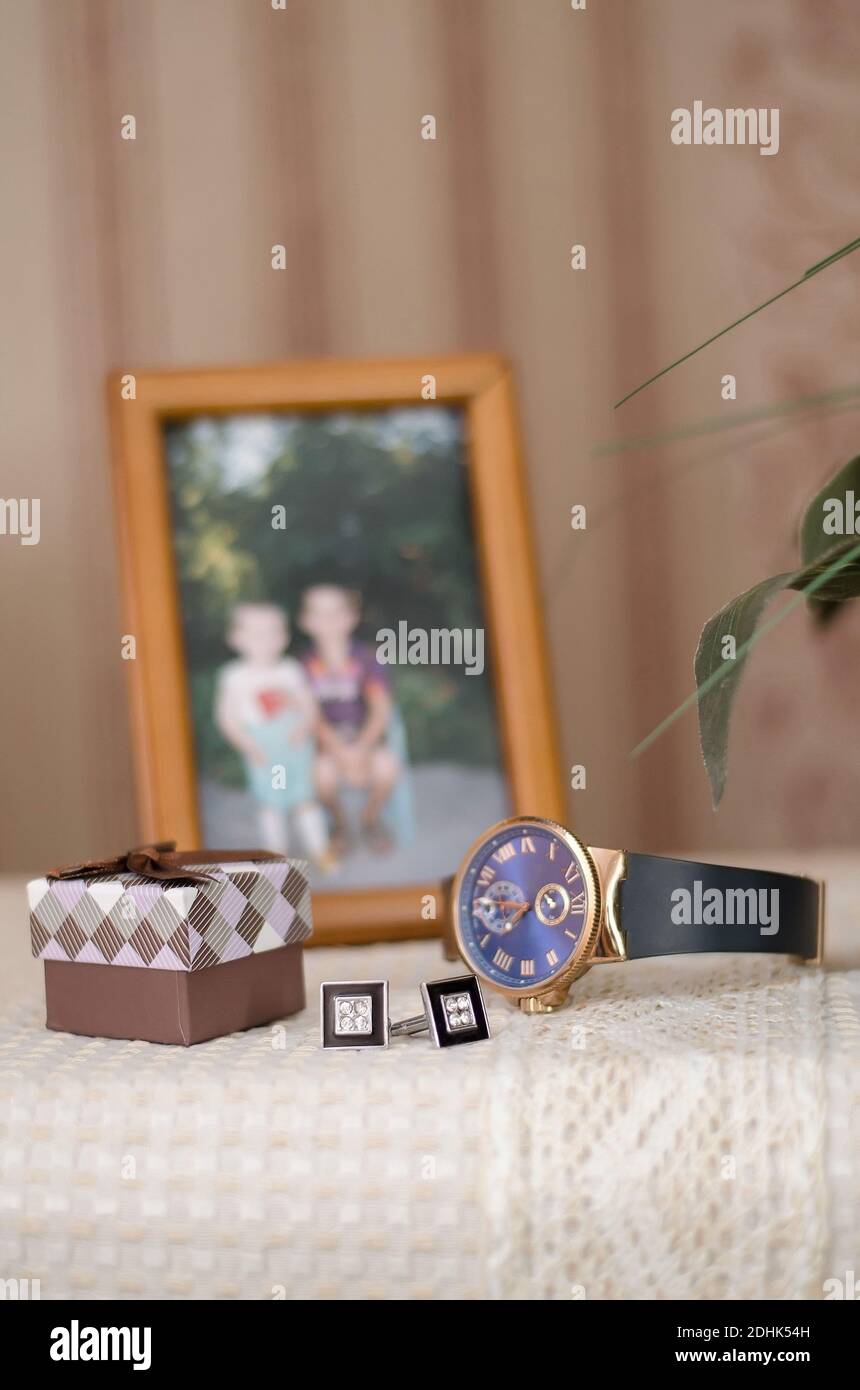 Hand-held men's watch, cufflinks, box, groom's accessories on the background of the photo, close-up Stock Photo