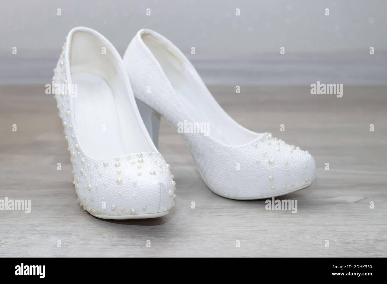 Bride's white wedding shoes with pearls are on the floor. Bride's accessories Stock Photo