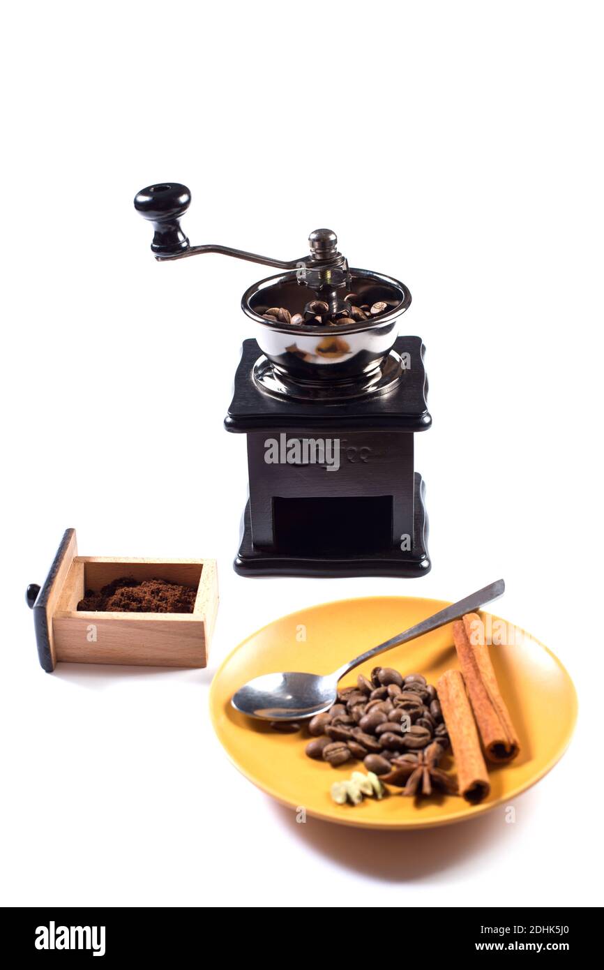Making turkish coffee with spices. Manual coffee grinder with coffee greains and different spices isolated on a white. Stock Photo