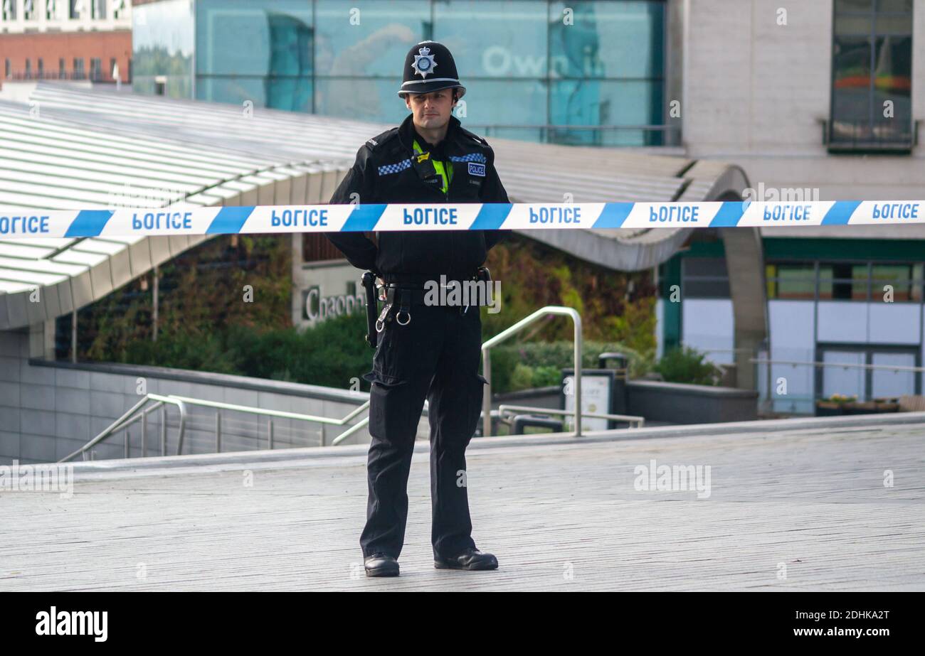 Policeman stands guard at police tape cordon, Birmingham City Centre, Bullring / Bull Ring Markets in October after a serious assault led to a man being hospitalised with head injuries. Birmingham, West Midlands, UK. Stock Photo