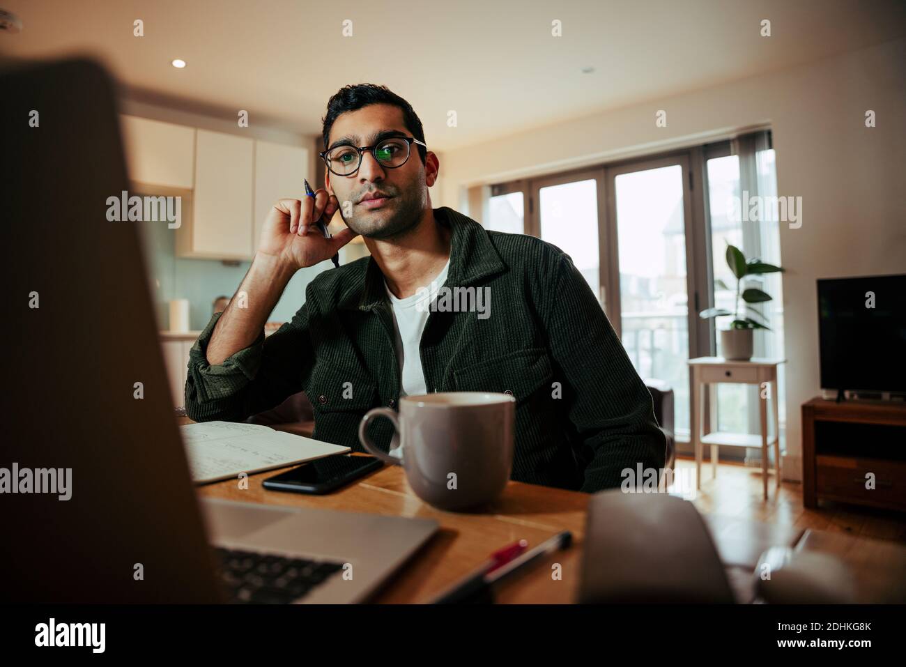 Mixed race businessman working from home office attending online meetings on desktop computer Stock Photo