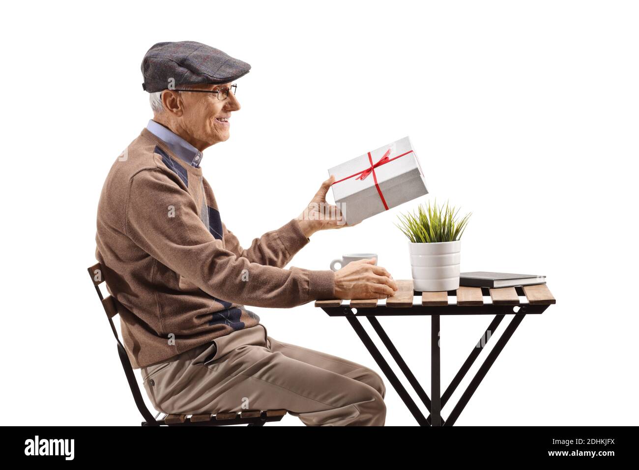 Elderly man sitting at a cafe and holding a present isolated on white background Stock Photo