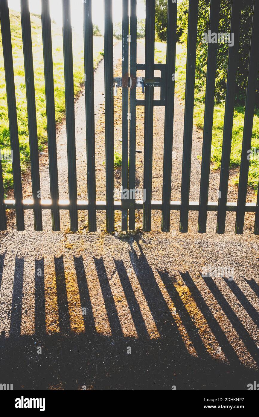 A pair of metal security gates casting a shadow on a path. Stock Photo