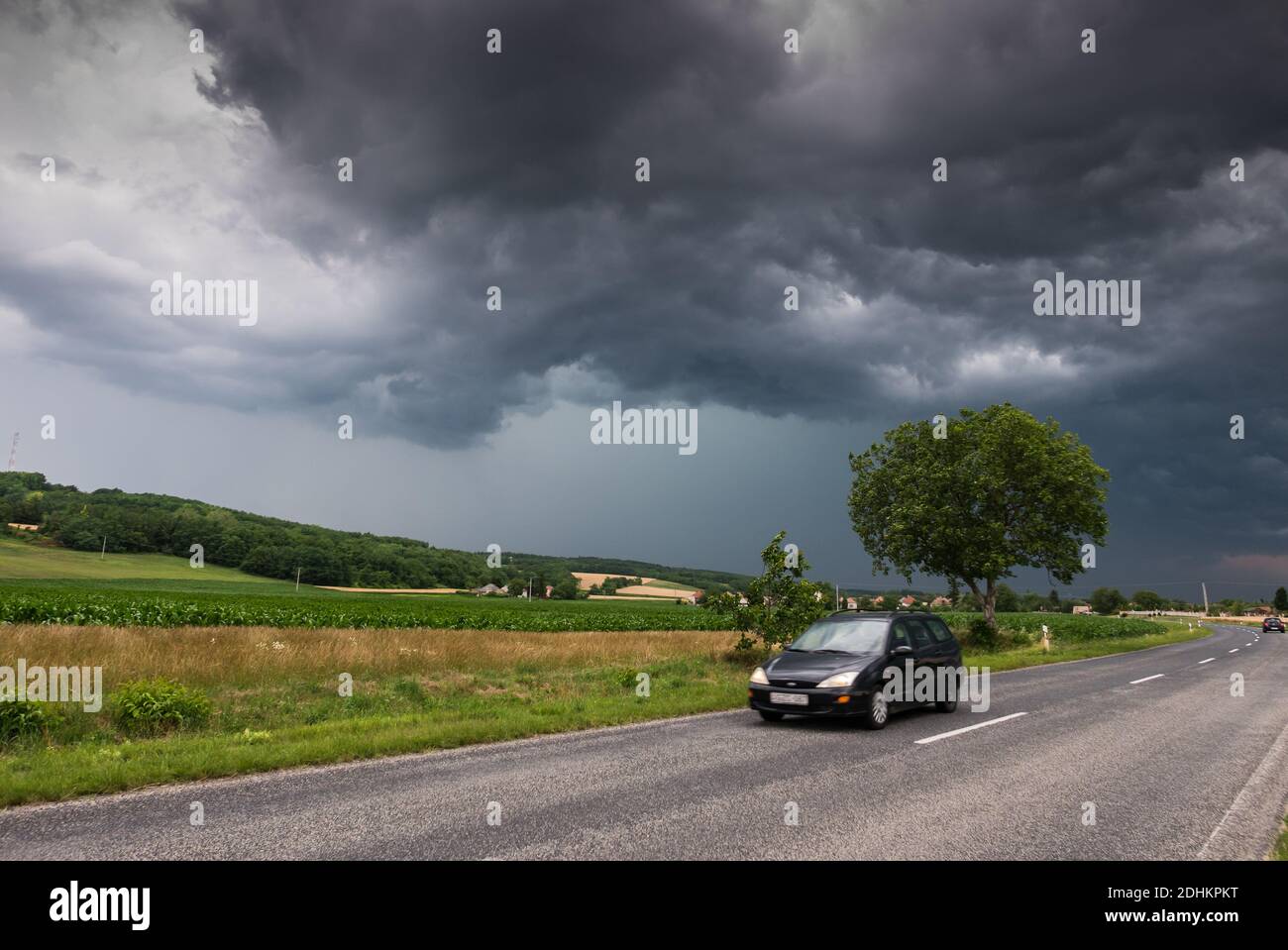 car on asphalt road under stormy sky with clouds Stock Photo - Alamy