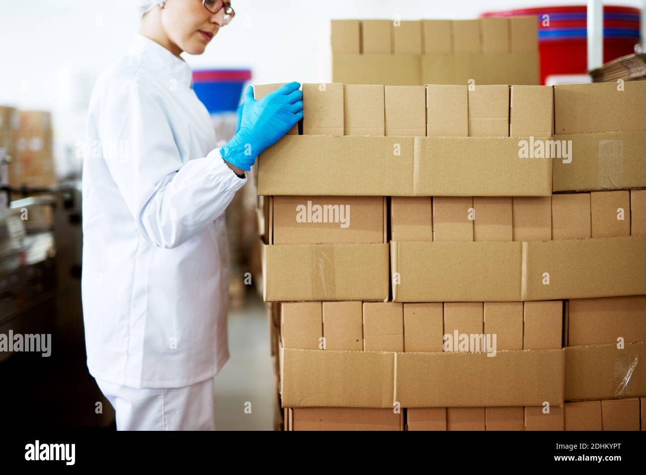 Young focused female worker in sterile cloths is folding boxes on ...