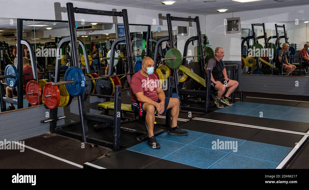 Man wearing face mask on gym weight lifting machine after lockdown easing during Covid-19 pandemic, North Berwick sports centre, Scotland, UK Stock Photo