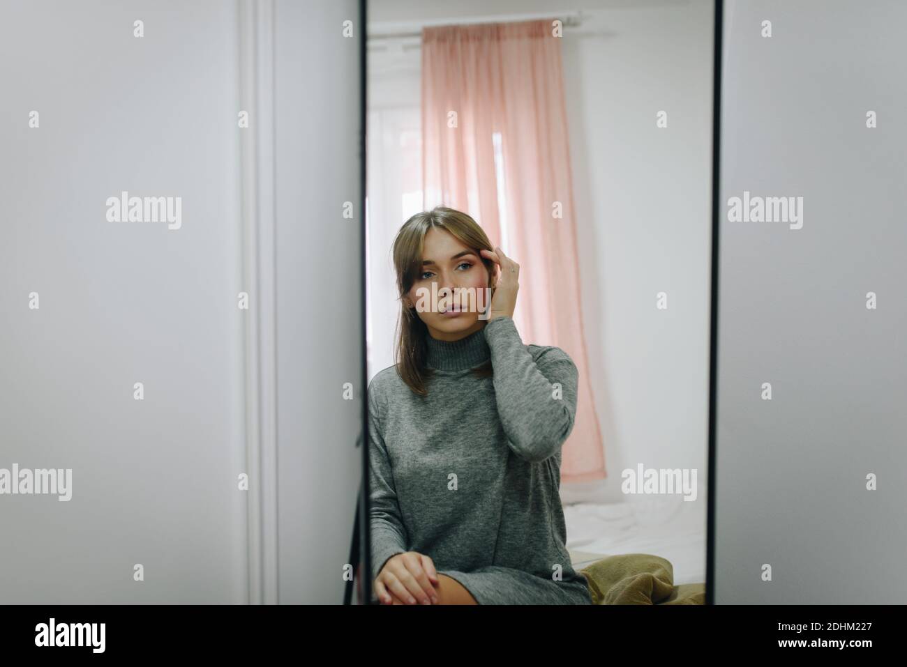 Blonde girl combing her hair in front of a mirror Stock Photo - Alamy