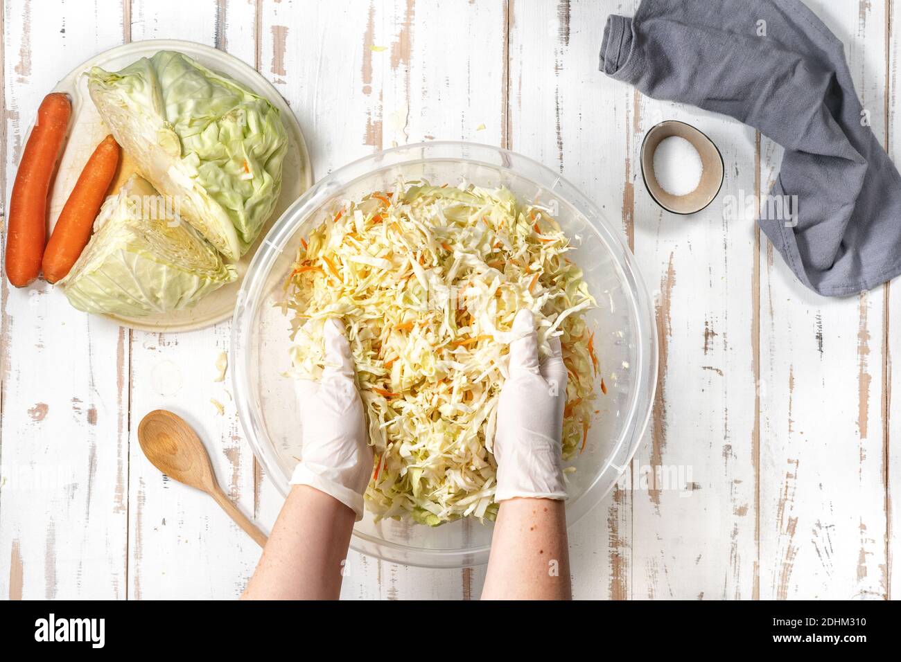 Female hands in gloves mixing chopped cabbage in a big bowl. Sauerkraut