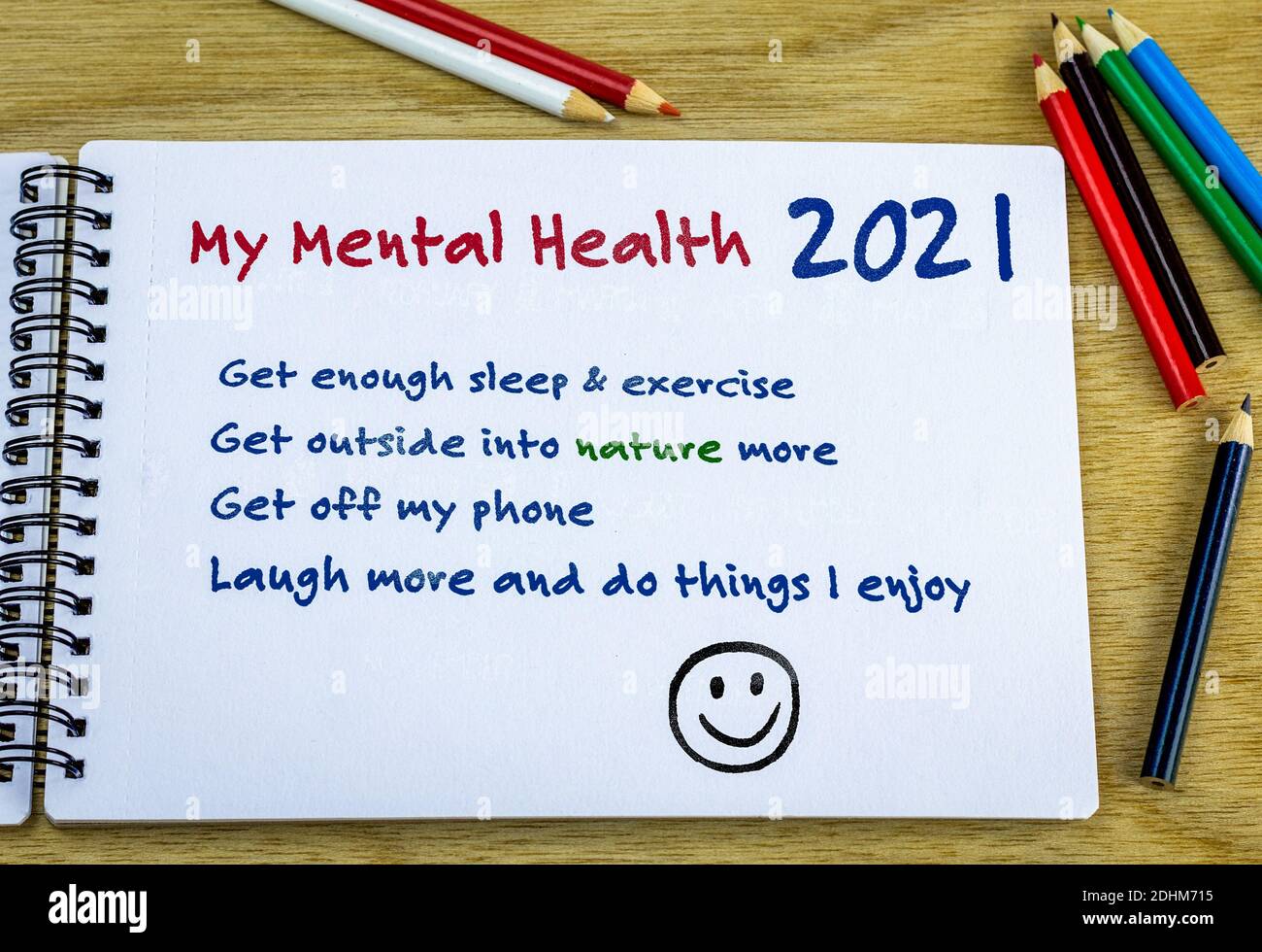 Mental health resolutions 2021 heading with list of ideas hand written in note book on desk. New year aspirations for wellbeing concept. Stock Photo
