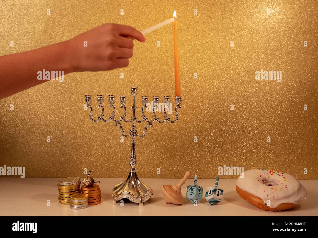 Day 1 of jewish religious holiday Hanukkah with child's hand lighting 1st candle in traditional