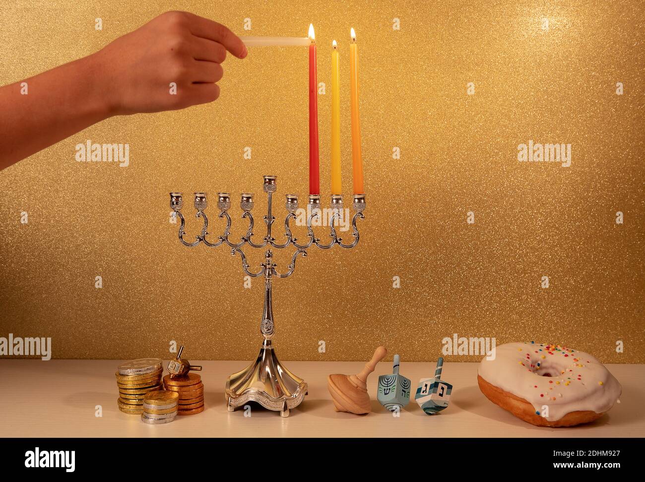 Day 3 of jewish religious holiday Hanukkah with child's hand lighting 3rd candle in traditional