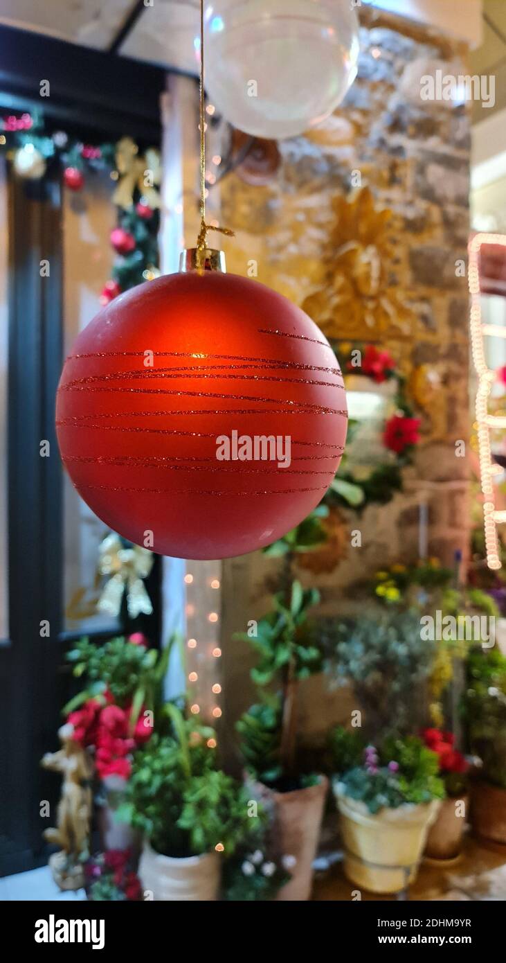 Red Christmas ball with blurred flower pots in the background Stock Photo