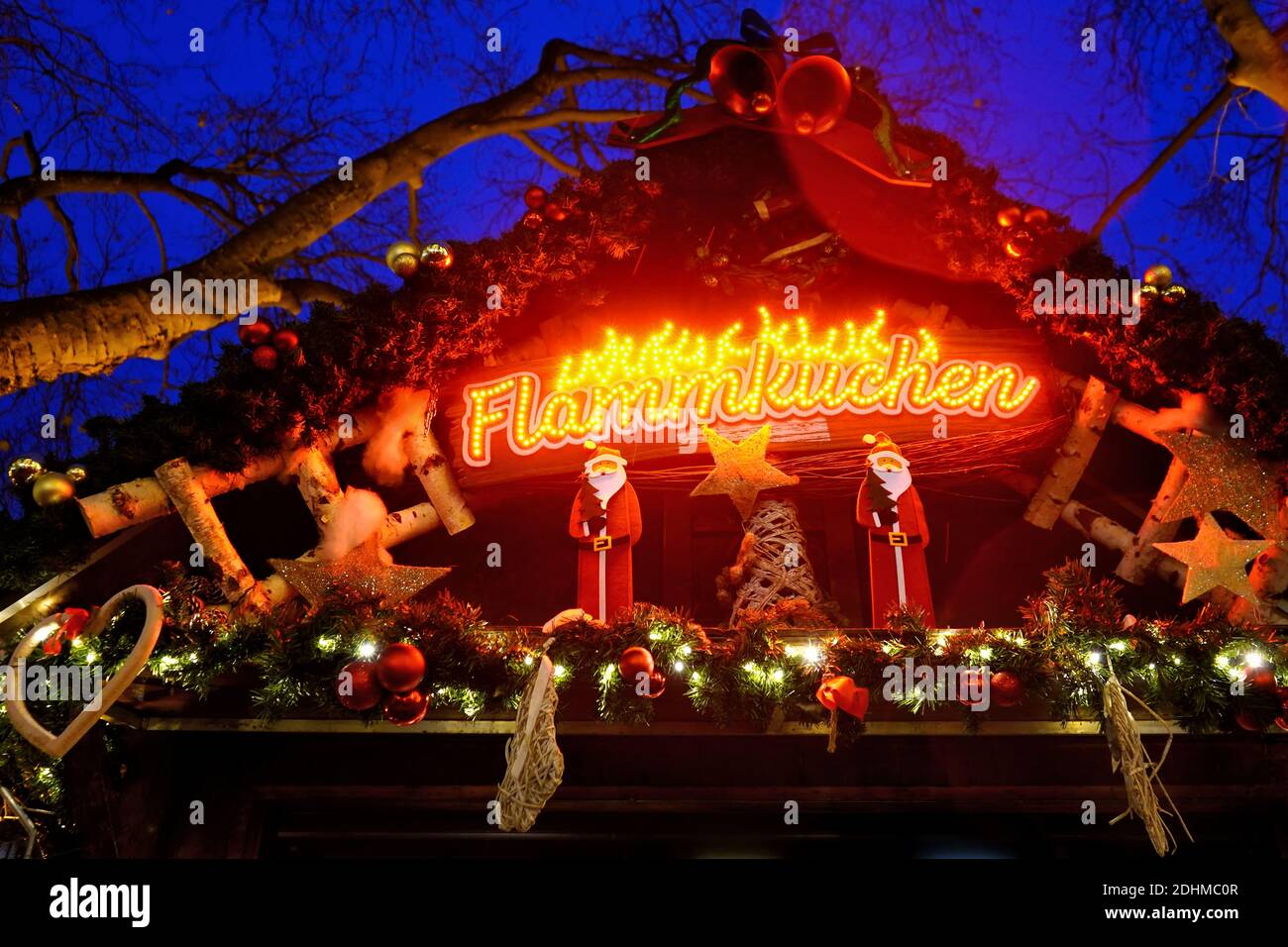 Close-up of an iIlluminated typical German Christmas market booth on Königsallee in Düsseldorf, selling Flammkuchen (tarte flambée). Stock Photo