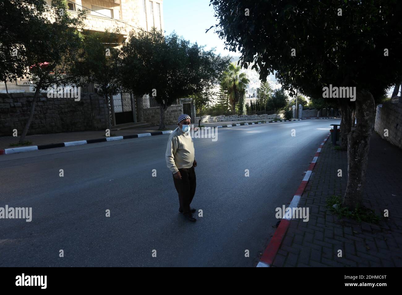 Nablus. 11th Dec, 2020. An elderly Palestinian man crosses an empty road in the West Bank city of Nablus, on Dec. 11, 2020. Palestine reported 1,743 new coronavirus cases, taking the tally of infections in the Palestinian territories to 121,157, including 1,029 deaths and 94,349 recoveries. Four Palestinian districts in the West Bank, including Nablus, Tulkarm, Bethlehem, and Hebron, went into a full weeklong lockdown that began on Thursday night. Credit: Ayman Nobani/Xinhua/Alamy Live News Stock Photo