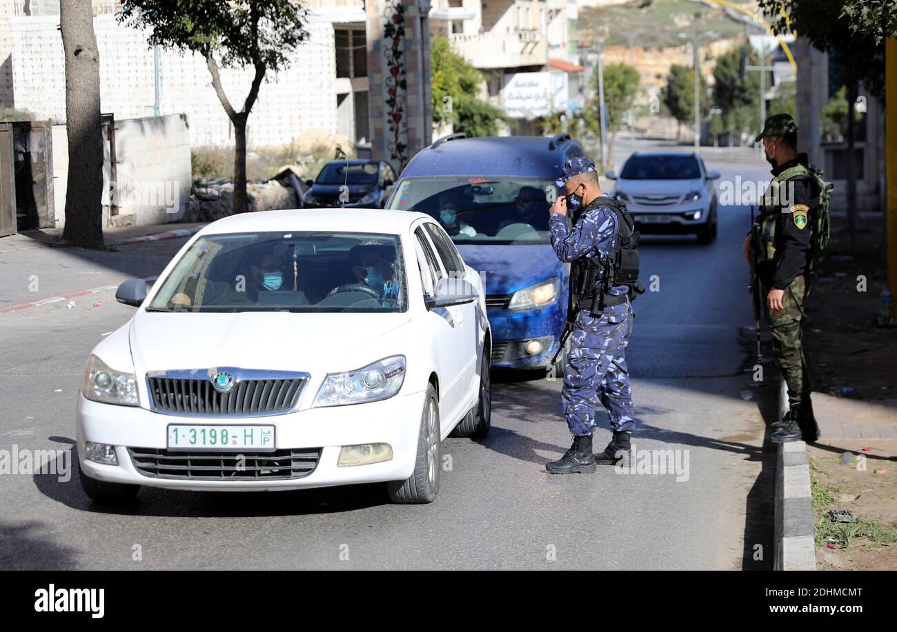 Hebron. 11th Dec, 2020. Palestinian policemen work on the road in the West Bank city of Hebron amid the lockdown imposed by the Palestinian authorities, on Dec. 11, 2020. Palestine reported 1,743 new coronavirus cases, taking the tally of infections in the Palestinian territories to 121,157, including 1,029 deaths and 94,349 recoveries. Four Palestinian districts in the West Bank, including Nablus, Tulkarm, Bethlehem, and Hebron, went into a full weeklong lockdown that began on Thursday night. Credit: Mamoun Wazwaz/Xinhua/Alamy Live News Stock Photo