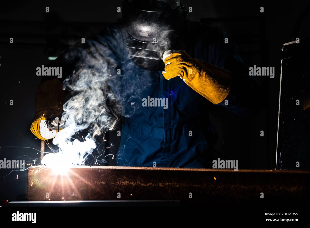 Metal welder working with arc welding machine to weld steel at factory
