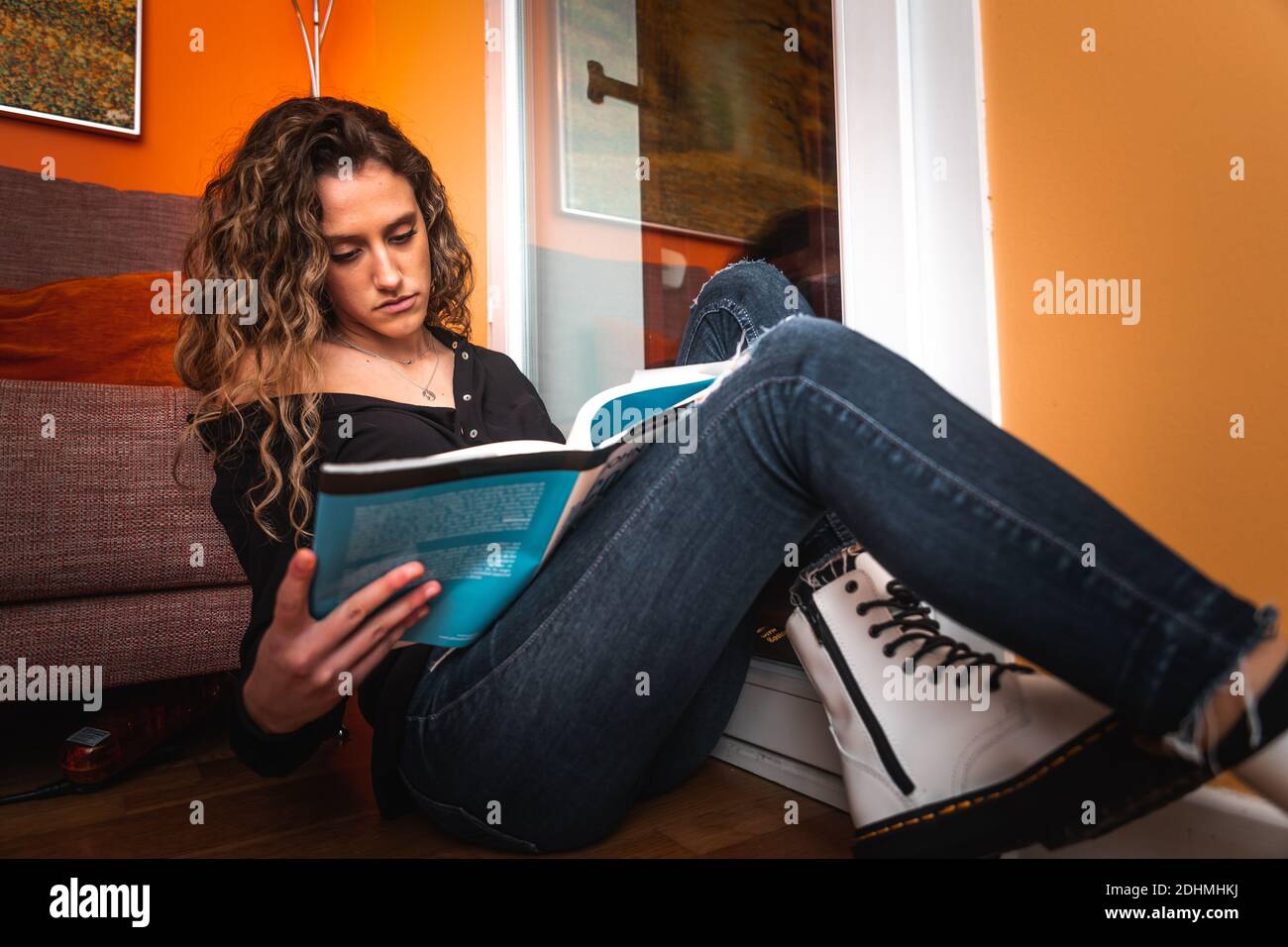 Young woman reading a book next to the window Stock Photo - Alamy