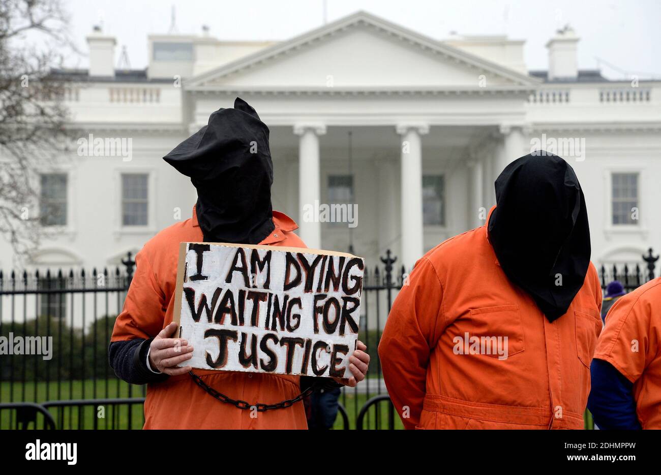 Protesters wearing orange jumpsuits and bags over their heads rally outside  of the White House to protest Guantanamo Bay on the incoming 14th  anniversary of the first prisoners arriving at the detention