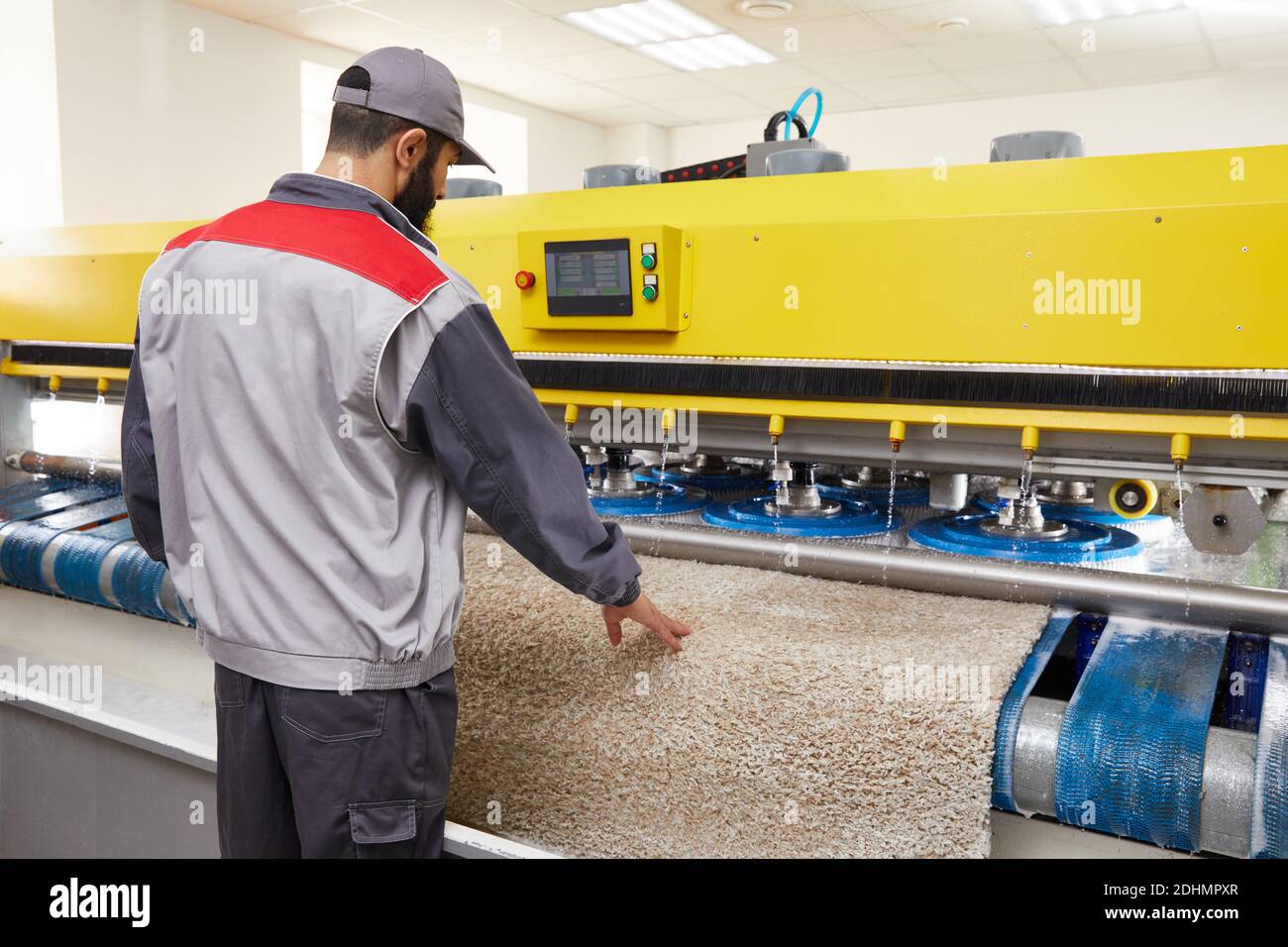 Man operating carpet automatic washing machine in professional laundry service Stock Photo